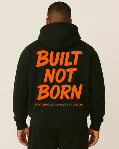 “Rückansicht eines schwarzen Notoriouz Sportswear Hoodies mit orangem BUILT NOT BORN Print aus der IRON GENESIS Kollektion.”